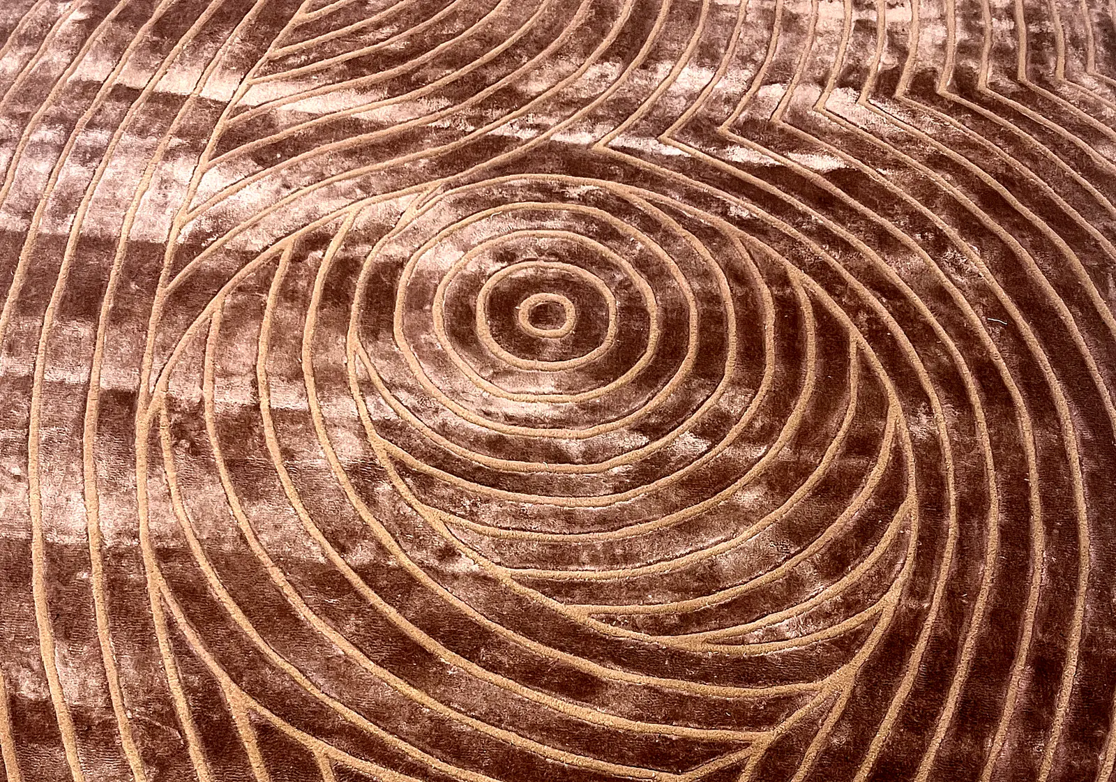 Detail of a carved spiral pattern in a rose-bronze wool rug